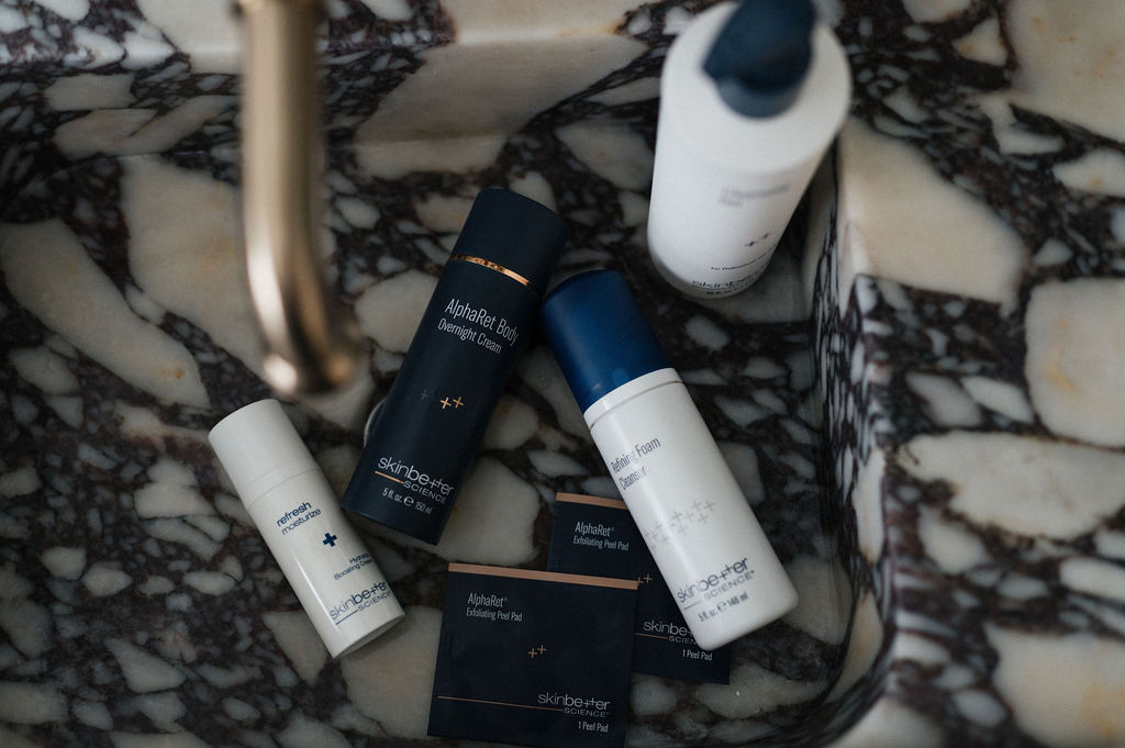Skinbetter Science skincare bottles and exfoliating pads arranged in a marble sink under a faucet
