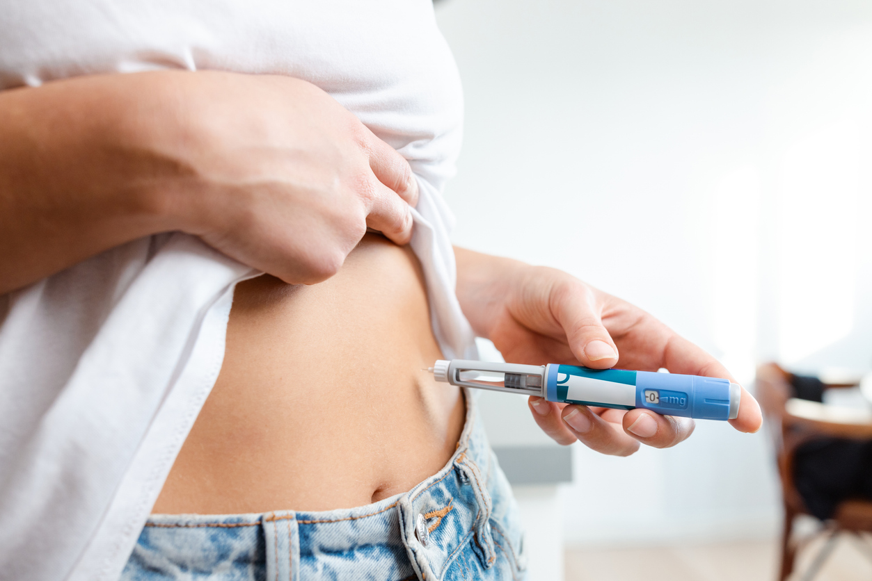 A woman self-injecting insulin into her abdomen with an insulin pen